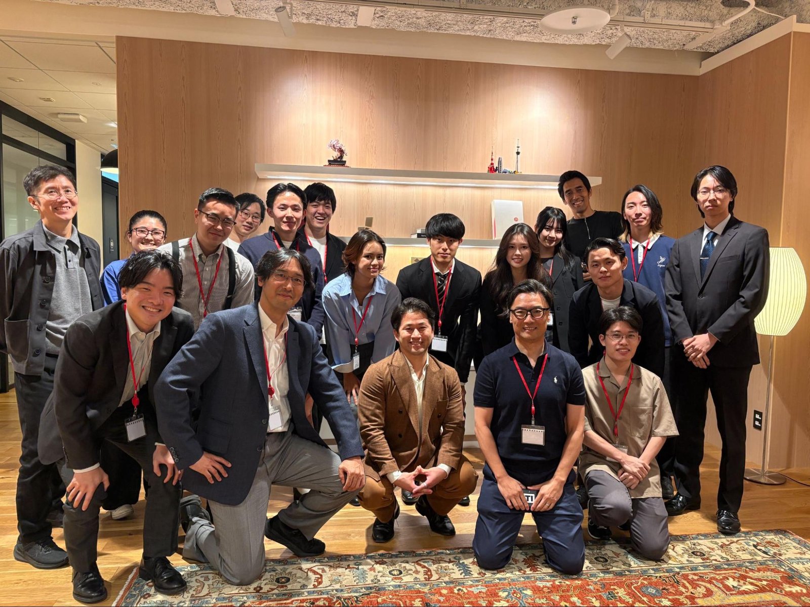 Notion 日本法人のオフィスで撮影した集合写真。琴坂研究会の学生と琴坂、Notion 日本法人と三菱商事の方々が木目の壁の前に並び、前列の参加者は柄物のラグの上にしゃがんでいる。